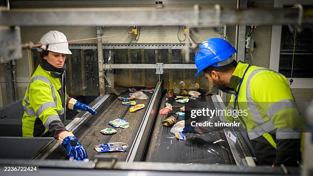 diverse employees sorting items on conveyor belt in waste management facility - circulaire economie stockfoto's en -beelden