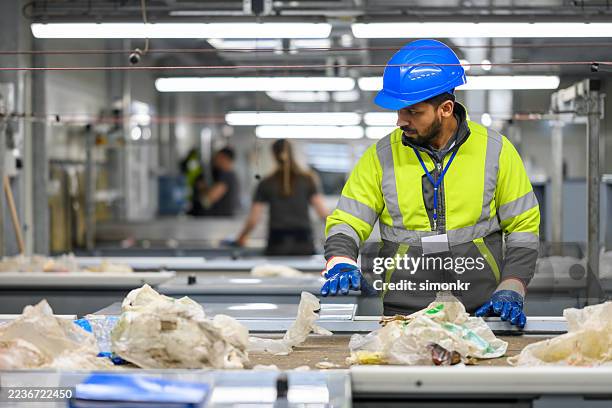 mid adult indian male sorting waste on conveyor belt - circulaire economie stockfoto's en -beelden