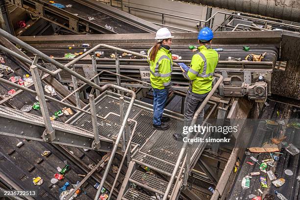 caucasian female and indian male engineers supervising waste management operations - circulaire economie stockfoto's en -beelden