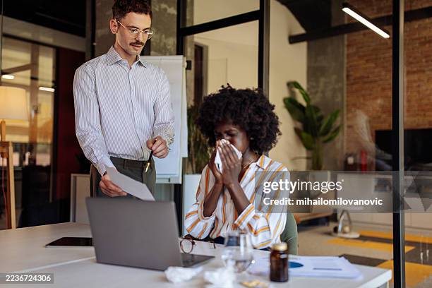 coworkers collaborating in office with concern over illness or health issues - sick leave stock pictures, royalty-free photos & images