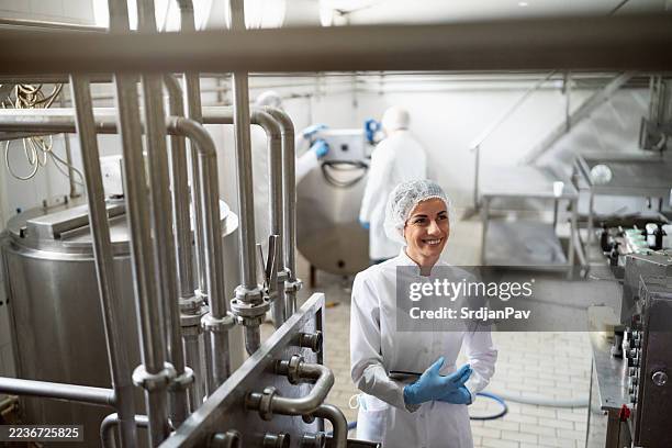 smiling staff member in a modern dairy processing facility - dairy factory worker stock pictures, royalty-free photos & images