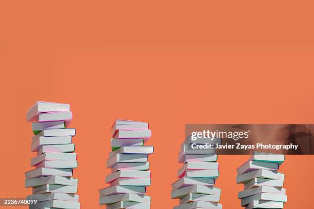 decreasing stacks of colorful books on orange background representing growth - knowledge is power stock pictures, royalty-free photos & images