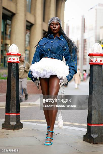 Annie Tagoe wearing silver rhinestone headscarf, denim cropped jacket, white ruffle mini skirt, white mini bag and blue heels outside Susan Fang...