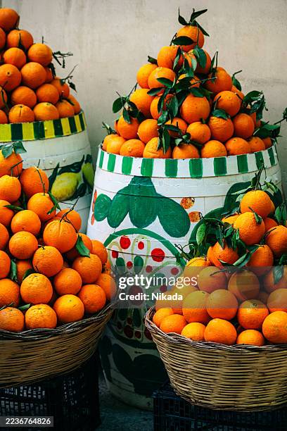 vibrant stacks of oranges in woven baskets and painted ceramic barrel in sicily market - trapani provincie stockfoto's en -beelden