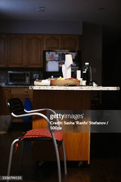 a messy kitchen counter and a chair in a home kitchen, with cabinets and appliances in the background - microwave mess stock pictures, royalty-free photos & images