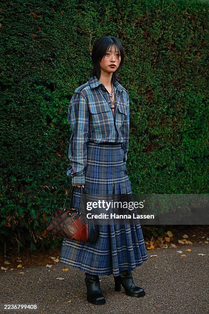 Guest wearing blue Burberry check shirt, matching maxi skirt, black boots and Burberry red check bag outside Burberry during London Fashion Week on...