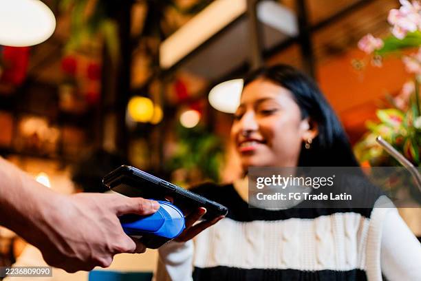 close-up of woman paying with contactless payment at coffee shop - tap to pay stock pictures, royalty-free photos & images