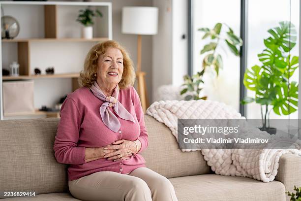 smiling elderly woman radiating comfort and joy - uncomfortable stock pictures, royalty-free photos & images