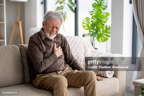 elderly man feeling emotional pain with hand on heart - chest pain stock pictures, royalty-free photos & images