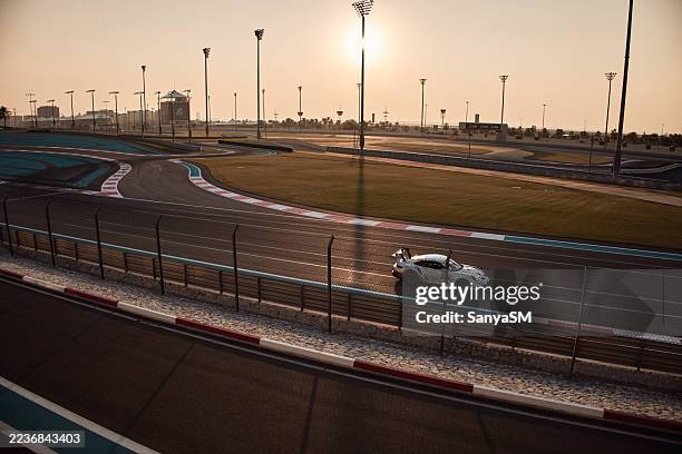 race car driving on yas marina circuit at sunset - formule 1 coureur stockfoto's en -beelden