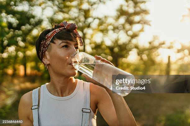woman drinking water outdoors finding refreshment and hydration - thirsty stock pictures, royalty-free photos & images