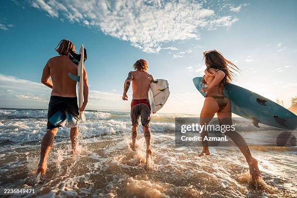 energetic caucasian friends surfing at sunrise - watersport stockfoto's en -beelden