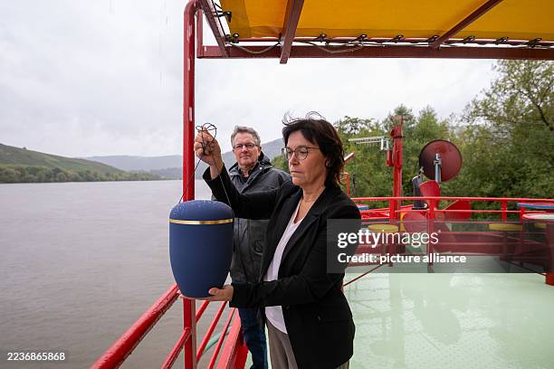 September 2025, Rhineland-Palatinate, Riol: Mortician Ulrike Grandjean shows how an urn burial on the Moselle takes place in the presence of captain...