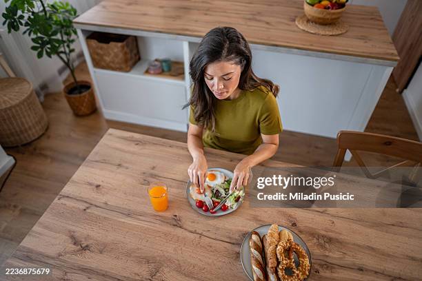mujer comiendo un desayuno saludable en la mesa de madera de la cocina - carbohidrato fotografías e imágenes de stock