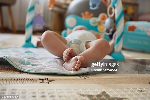 baby playing on mat with feet visible - play mat stock pictures, royalty-free photos & images