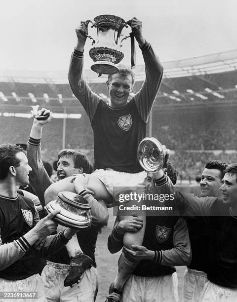 West Ham captain Bobby Moore lifting the FA Cup trophy at Wembley Stadium in London, May 2nd 1964. Teammate Ken Brown is holding the base of the...