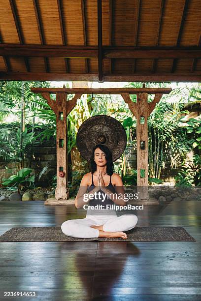 woman meditating in lotus pose at yoga retreat - lotus position stock pictures, royalty-free photos & images