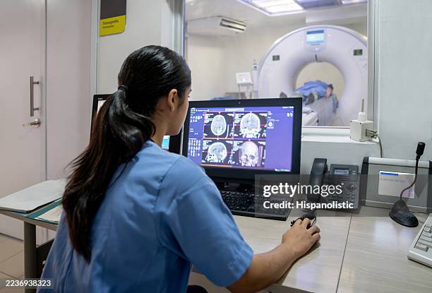 radiologist performing a brain cat scan at the hospital - brain tumour stock pictures, royalty-free photos & images