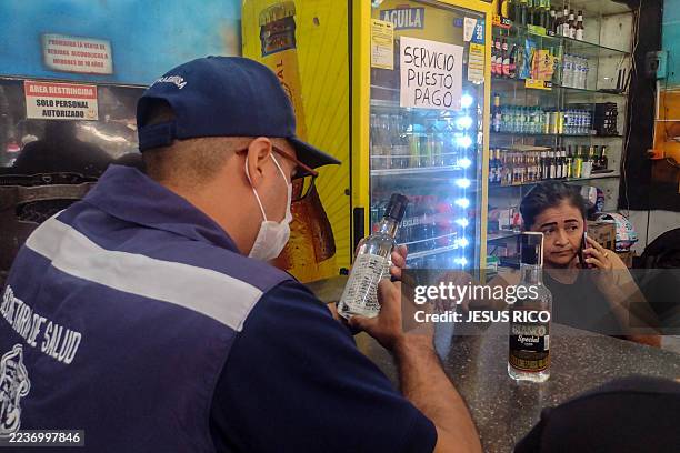 Barranquilla's Health Secretariat inspector checks a liquor bottle at the Boliche area in Barranquilla, Colombia on September 25, 2025. According to...