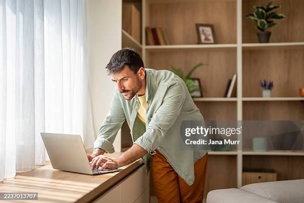 freelancer enfocado trabajando desde casa en una computadora portátil por ventana - broma pesada fotografías e imágenes de stock