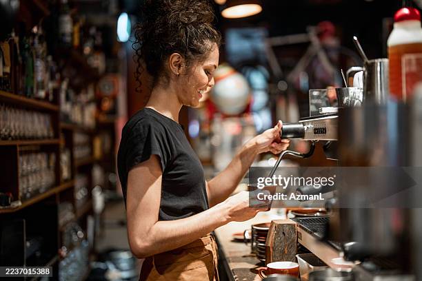 young aboriginal barista carefully preparing fresh coffee in cozy cafe - coffee shop stock pictures, royalty-free photos & images