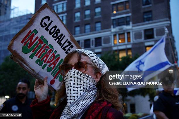 Pro-Palestinian activist holds a sign during the "Autonomous Noise Demonstration for Gaza" near supporters of Israel holding Israeli flags outside...
