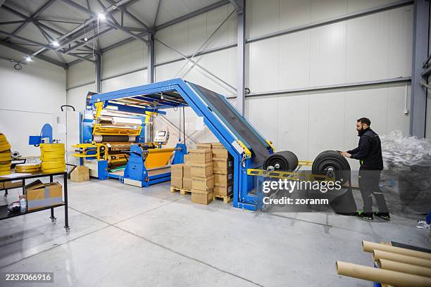 industrial packaging line with blue conveyor and worker in modern warehouse - corrugated cardboard stock pictures, royalty-free photos & images