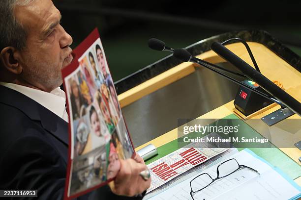 President of Iran Masoud Pezeshkian holds up pictures as he speaks during the United Nations General Assembly at the United Nations headquarters on...
