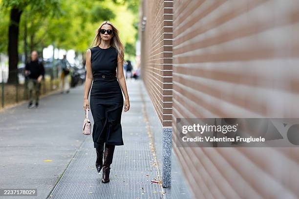 Simona Jakstaite wears a black sunglasses, a light pink Fendi Baguette leather bag, bordeaux leather knee high heeled boots and a Fendi sleeveless...