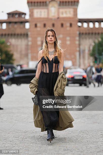 Guest wears long wavy shoulder-length hair with dark roots and blonde ends, center part, a silver-tone multi-strand necklace, a black-and-white zebra...
