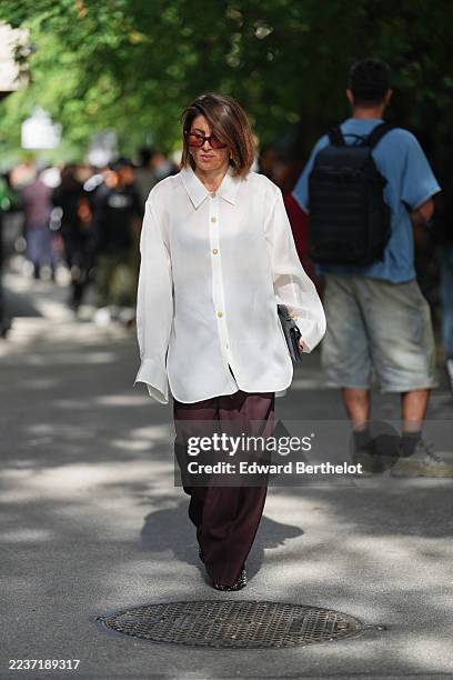 Guest wears a shoulder-length brown bob with a side part, brown-tinted rectangular sunglasses, a thin gold chain necklace, a black leather clutch...