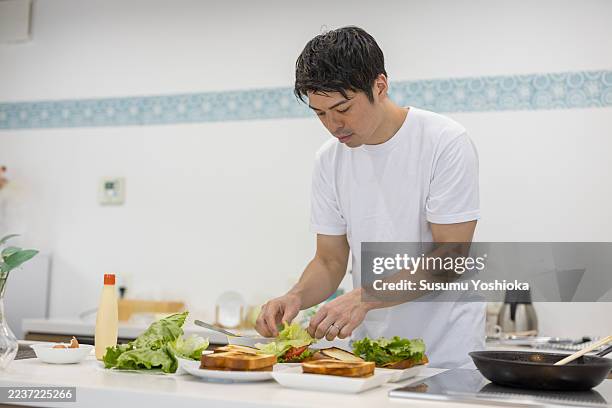 a couple prepares a meal together in their home kitchen. - making a sandwich stock pictures, royalty-free photos & images
