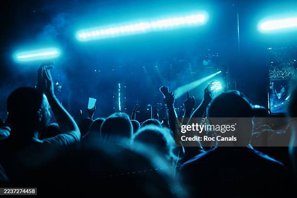 concert crowd cheering under blue stage lights - locale notturno foto e immagini stock