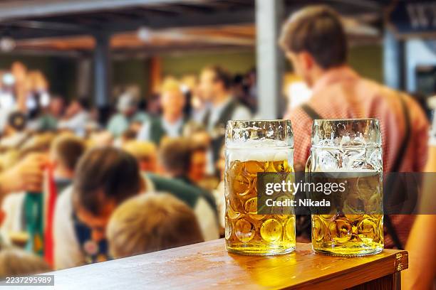 due grandi boccali di birra su un bar al famoso festival della birra di monaco di baviera - tradizione foto e immagini stock