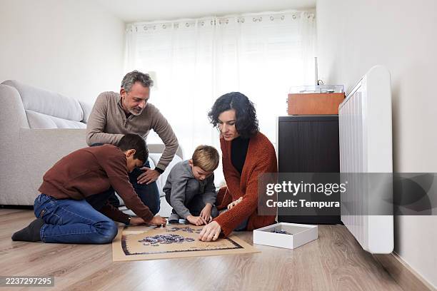 a lovely family enjoying a fun puzzle together at home. - four people stock pictures, royalty-free photos & images
