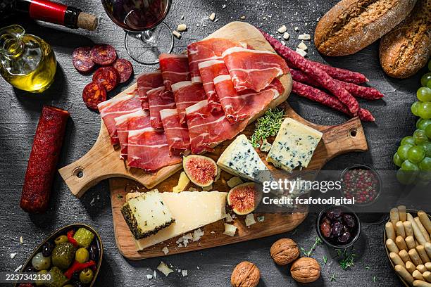 delicioso aperitivo típico mediterráneo. jamón curado, chorizo y una variedad de quesos. antipasti o tapas. tabla de embutidos y quesos con fruta - jamón de parma fotografías e imágenes de stock