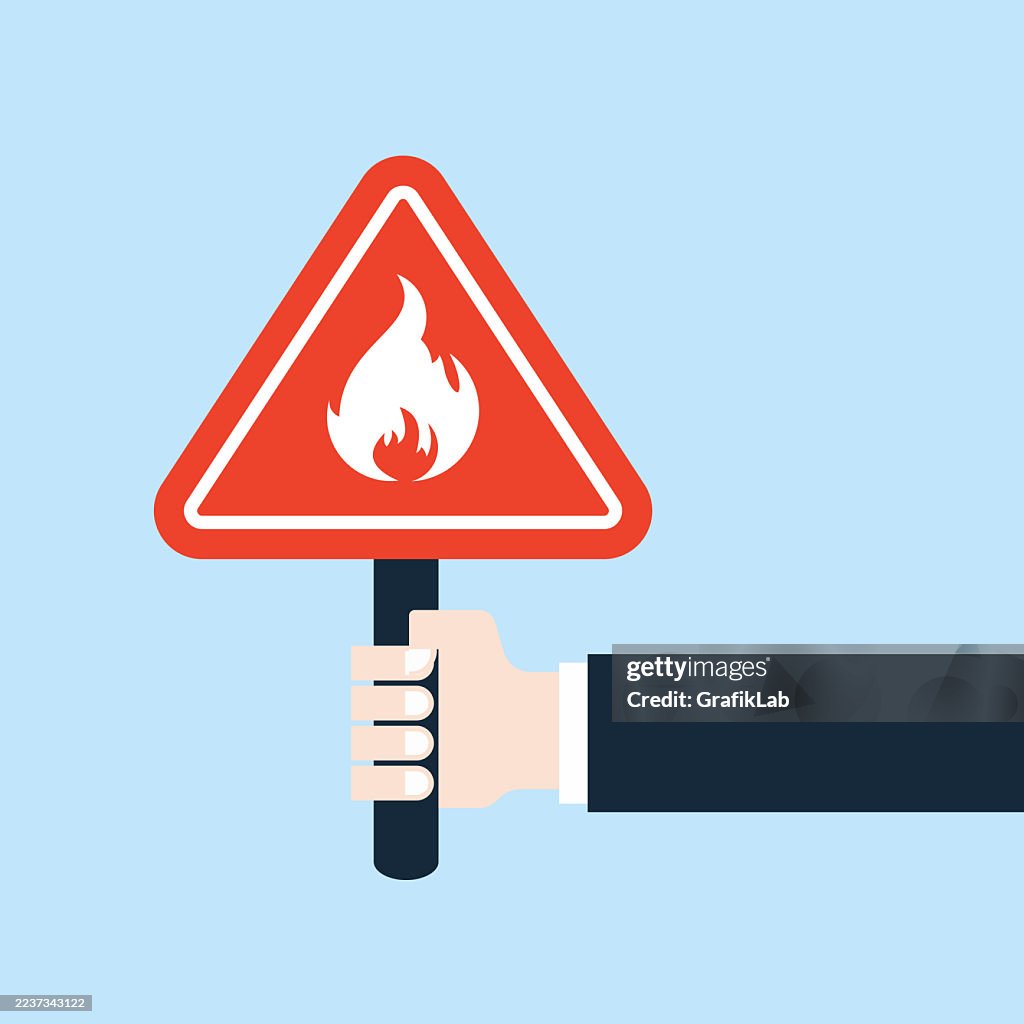 Red Warning Sign Depicting Fire Held by Businessman's Hand Vector