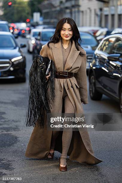 Guest wears oversized brown coat, belt, black bag with fringes, wool tights outside Max Mara during the Milan Fashion Week Womenswear Spring/Summer...