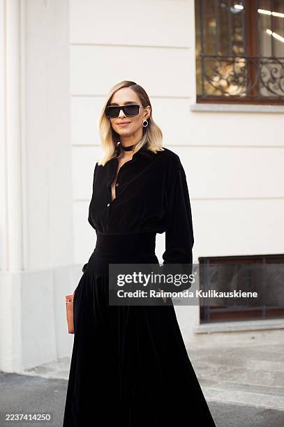 Candela Pelizza wears a black velvet blouse with matching high-waisted maxi skirt, styled with black sunglasses, gold hoop earrings, a pale pink...