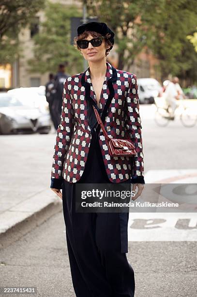 Irina Kro Eicke wears a red and grey check blazer with black wide-leg trousers, styled with a navy beret, black sunglasses, a red quilted handbag,...