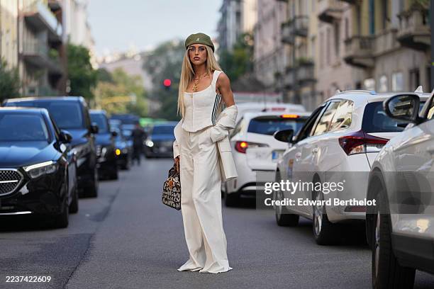 Emili Sindlev wears long straight blonde hair with a center part, layered gold necklaces including a cross pendant, a brown Louis Vuitton & Stephen...
