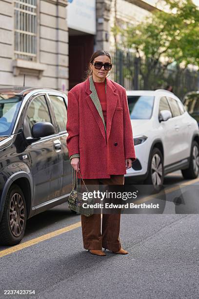 Guest wears a slicked-back low bun hairstyle, oversized dark brown sunglasses, gold hoop earrings and gold rings and a gold bracelet, a green and...