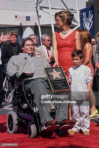 American actor Christopher Reeve, wearing a grey sweater and grey trousers, with his wife, American actress and singer Dana Reeve, and their son,...