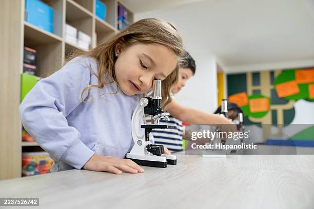 primary school students looking through microscopes in science class - primary school science stock pictures, royalty-free photos & images