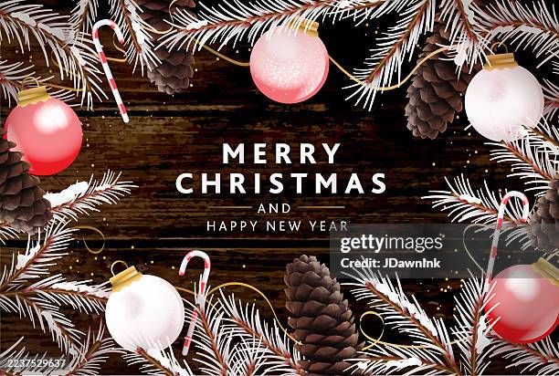 merry christmas greeting greeting background with decorations ornaments, pine branches, candy canes, golden glitter ribbons and pine cones on wooden background - rustic christmas pattern stock illustrations