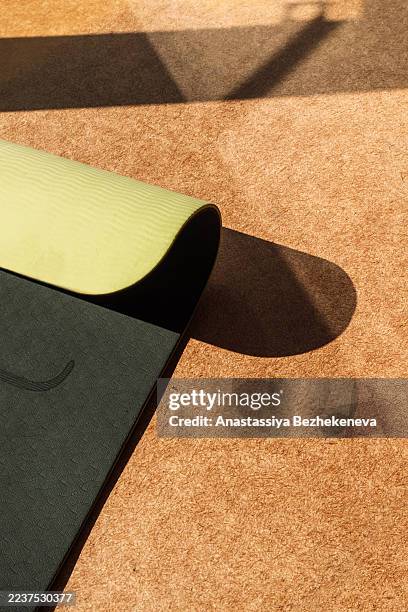 unrolled yoga mat with hard sunlight, minimal fitness scene. - estera fotografías e imágenes de stock