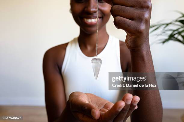 woman using crystal pendulum for dowsing and spiritual wellness - pendel stock-fotos und bilder