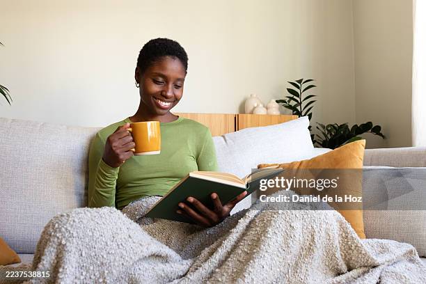 young woman enjoying cozy reading time at home - warm clothing stock pictures, royalty-free photos & images