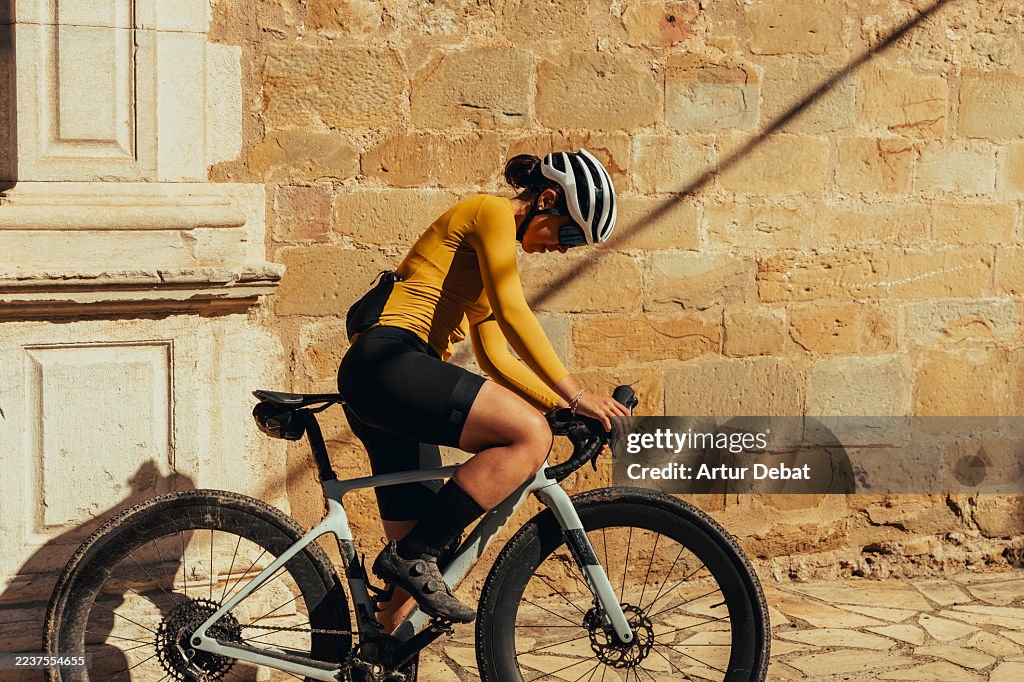 Female gravel cyclist ready to ride in front of historic stone wall visiting Catalonia