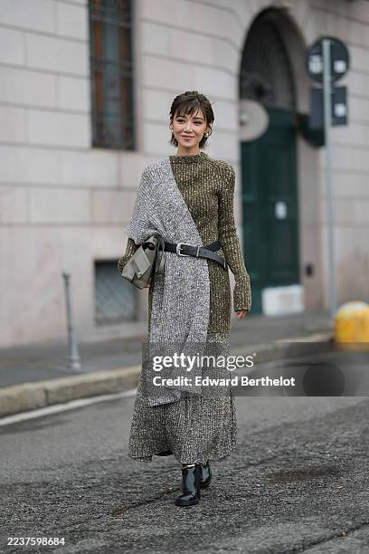 Elva Ni wears short layered brown hair with bangs, white pearl earrings, a gray leather shoulder bag, a metallic olive-green ribbed knit long-sleeve...